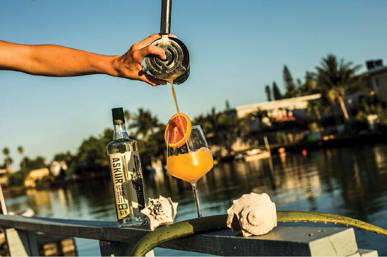 Cocktail being poured beside a bottle of Askur Gin